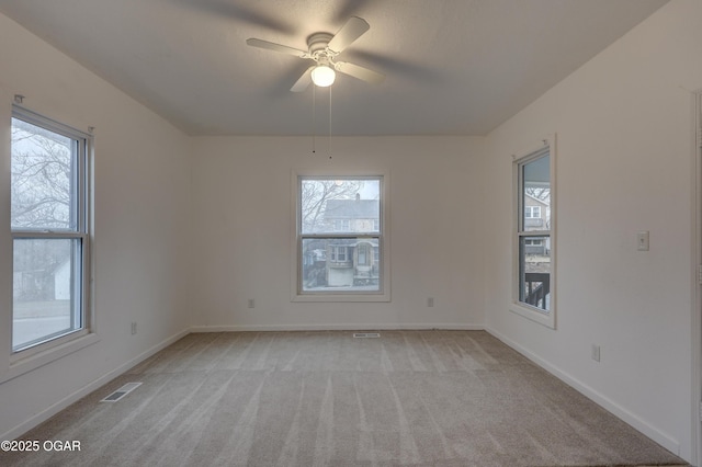 carpeted spare room with ceiling fan and plenty of natural light