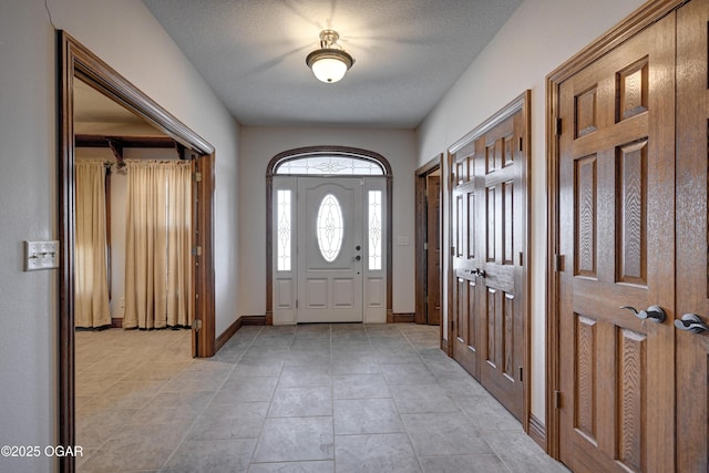 foyer featuring light tile patterned flooring and a textured ceiling