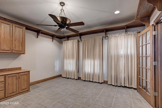 interior space with a textured ceiling and ceiling fan