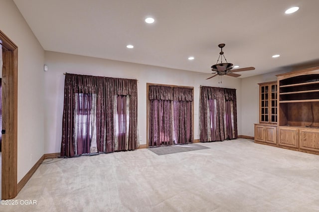 unfurnished living room featuring ceiling fan and light carpet