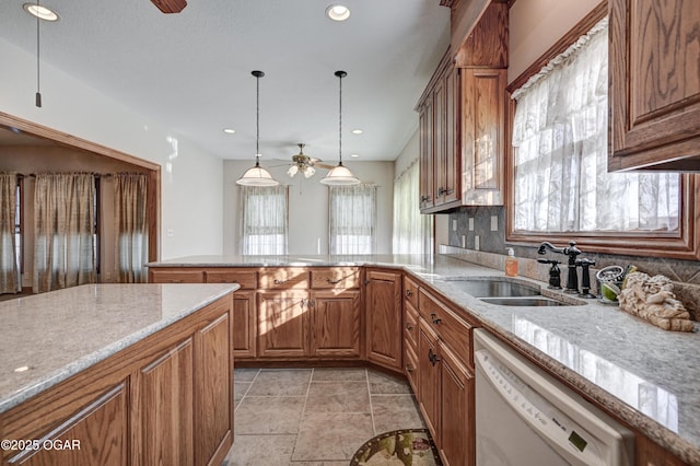 kitchen featuring decorative light fixtures, sink, ceiling fan, light stone counters, and white dishwasher