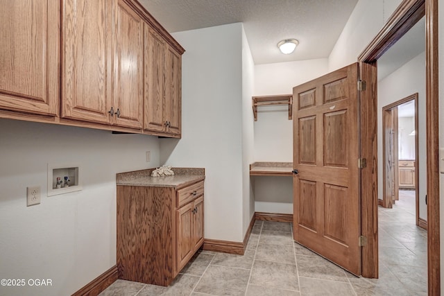 washroom with hookup for a washing machine, cabinets, and a textured ceiling