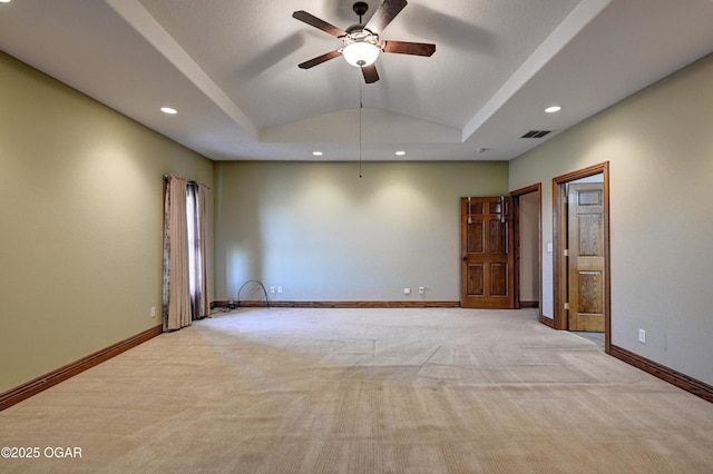 unfurnished room featuring ceiling fan, light colored carpet, lofted ceiling, and a raised ceiling