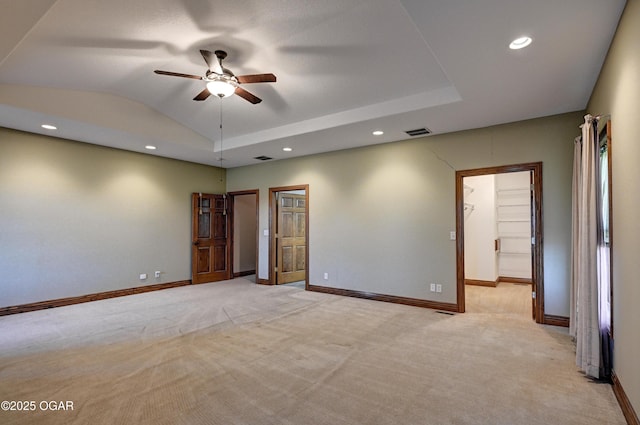 spare room with lofted ceiling, a tray ceiling, light colored carpet, and ceiling fan