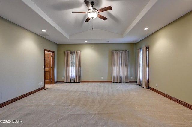 carpeted spare room featuring vaulted ceiling, a raised ceiling, and ceiling fan