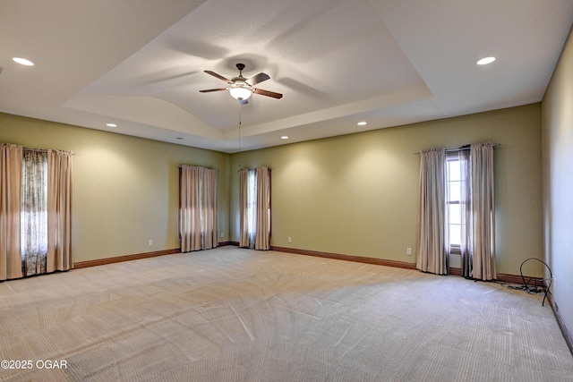 spare room with a raised ceiling, lofted ceiling, light colored carpet, and ceiling fan