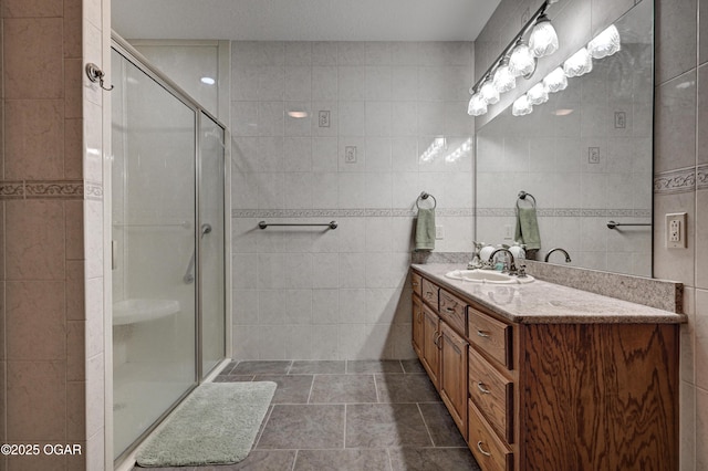 bathroom featuring tile walls, vanity, and a shower with shower door