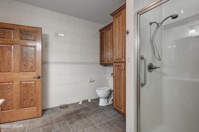 bathroom featuring toilet, a shower with shower door, tile walls, and a textured ceiling