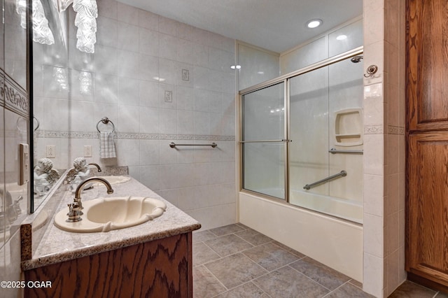 bathroom featuring vanity, combined bath / shower with glass door, and tile walls