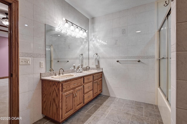 bathroom with tile walls, vanity, tile patterned flooring, and combined bath / shower with glass door