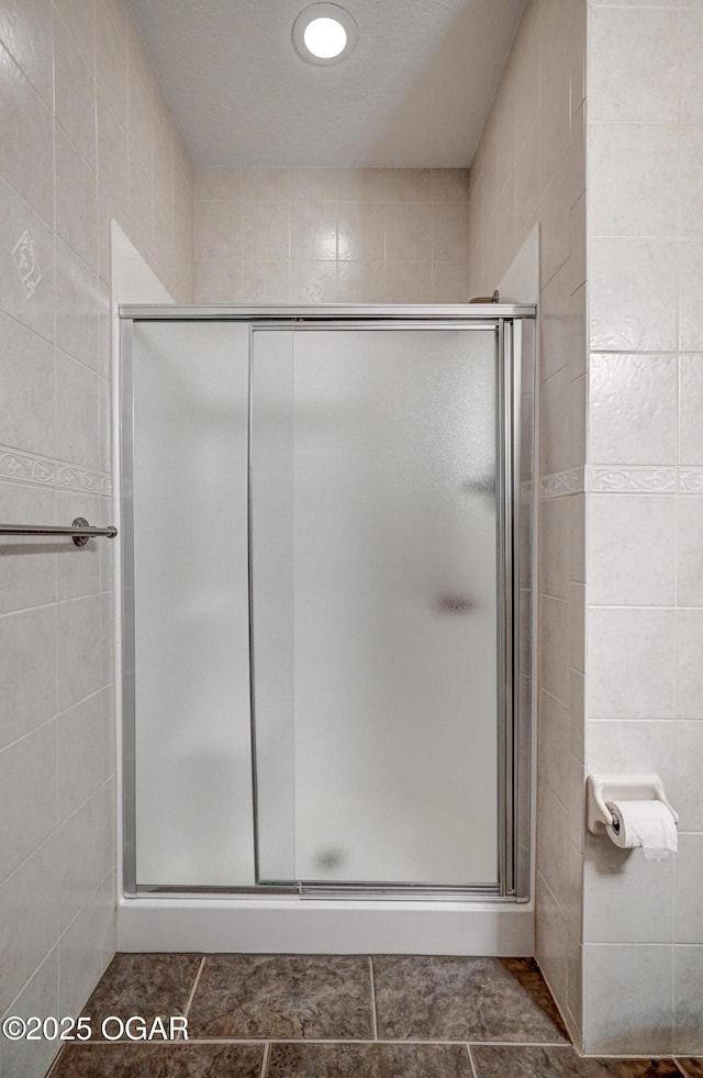 bathroom with tile walls, tile patterned floors, and a shower with door