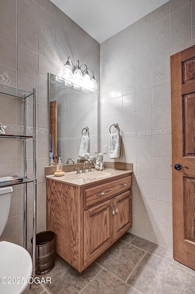 bathroom featuring vanity, toilet, tile patterned flooring, and tile walls