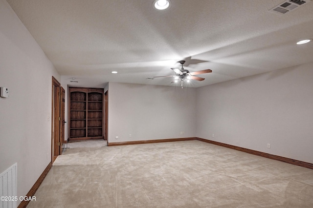 carpeted spare room with ceiling fan and a textured ceiling