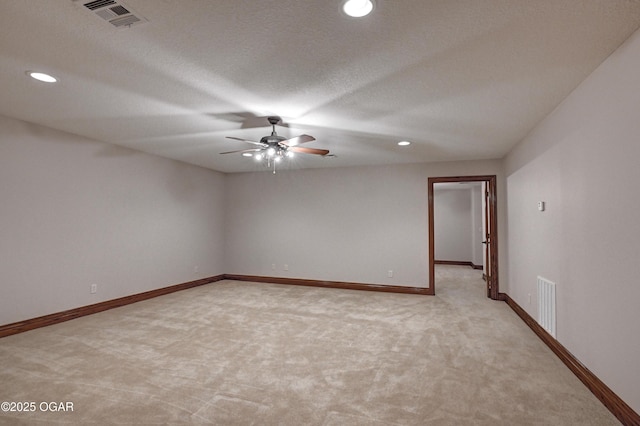 spare room featuring ceiling fan, light carpet, and a textured ceiling