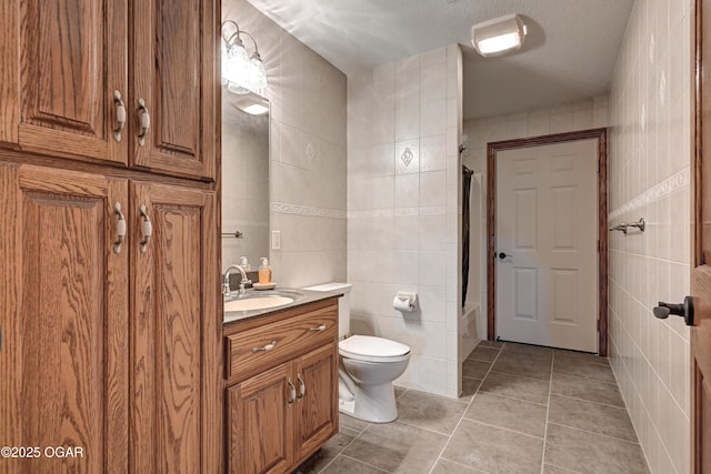 bathroom with tile walls, vanity, tile patterned floors, and toilet