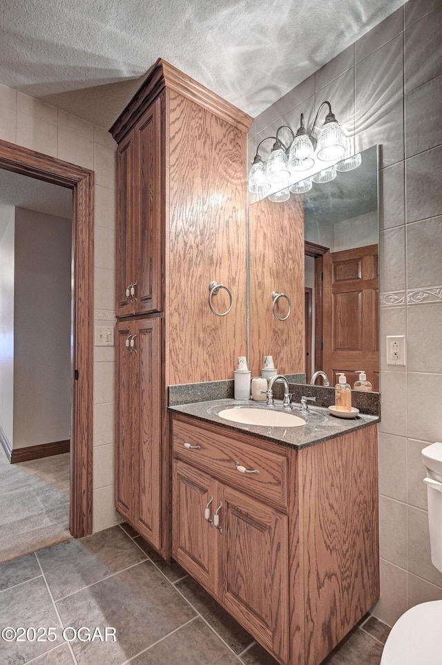 bathroom featuring tile walls, tile patterned flooring, vanity, a textured ceiling, and toilet