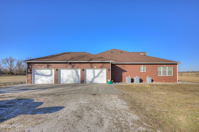 rear view of property with a garage and central AC