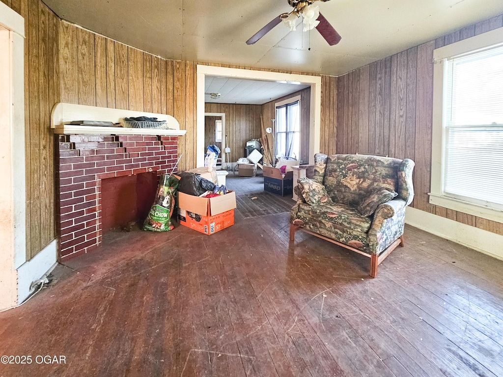 living room featuring a fireplace, wood-type flooring, wooden walls, and ceiling fan