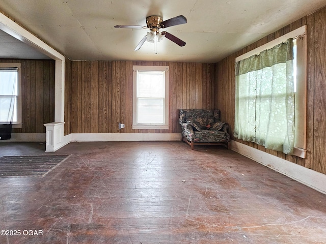 unfurnished room featuring wooden walls and ceiling fan