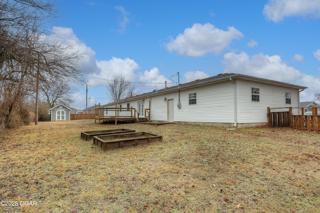 rear view of property with a wooden deck, a storage unit, and a lawn