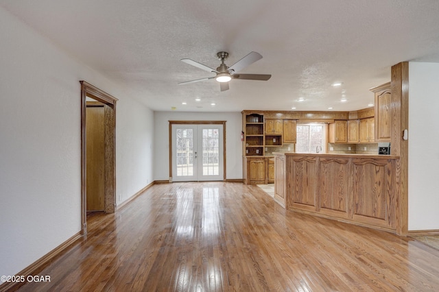 kitchen featuring light wood-type flooring, a wealth of natural light, kitchen peninsula, and french doors