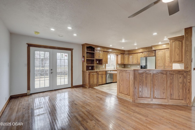 kitchen with french doors, stainless steel appliances, kitchen peninsula, and light wood-type flooring