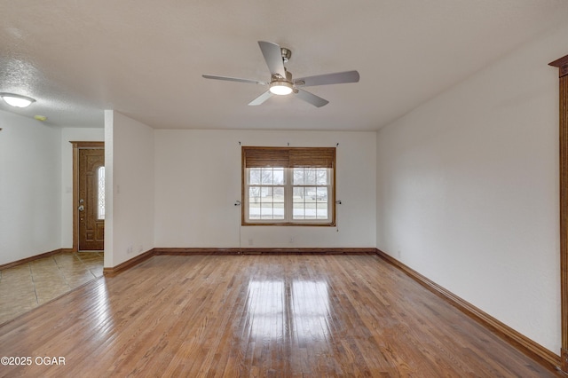 unfurnished room with ceiling fan, a textured ceiling, and light wood-type flooring