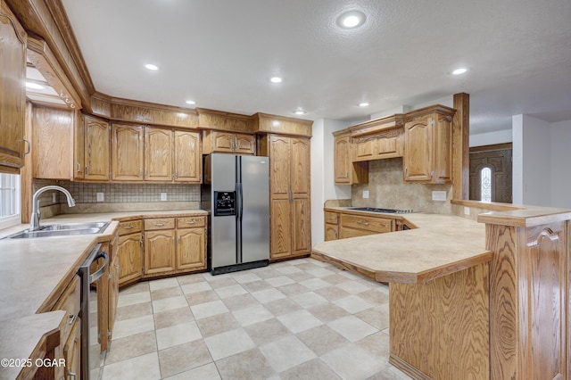 kitchen with sink, backsplash, kitchen peninsula, and appliances with stainless steel finishes