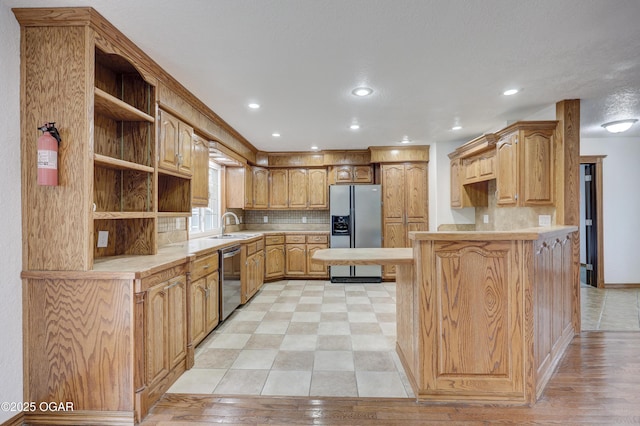 kitchen with backsplash, sink, kitchen peninsula, and appliances with stainless steel finishes