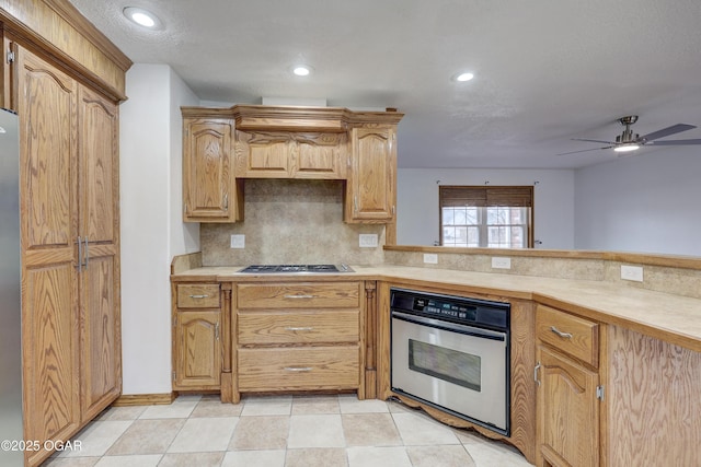 kitchen with appliances with stainless steel finishes, ceiling fan, and decorative backsplash