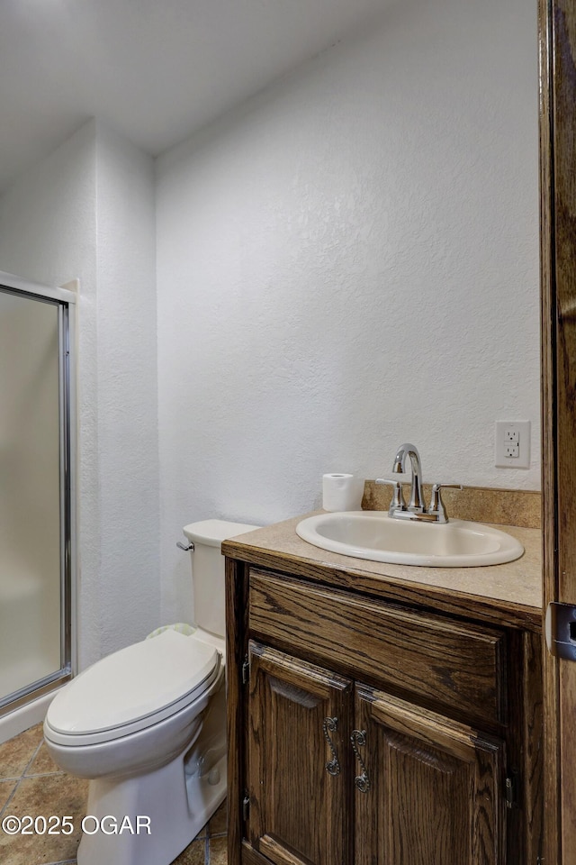 bathroom featuring a shower with door, vanity, tile patterned flooring, and toilet