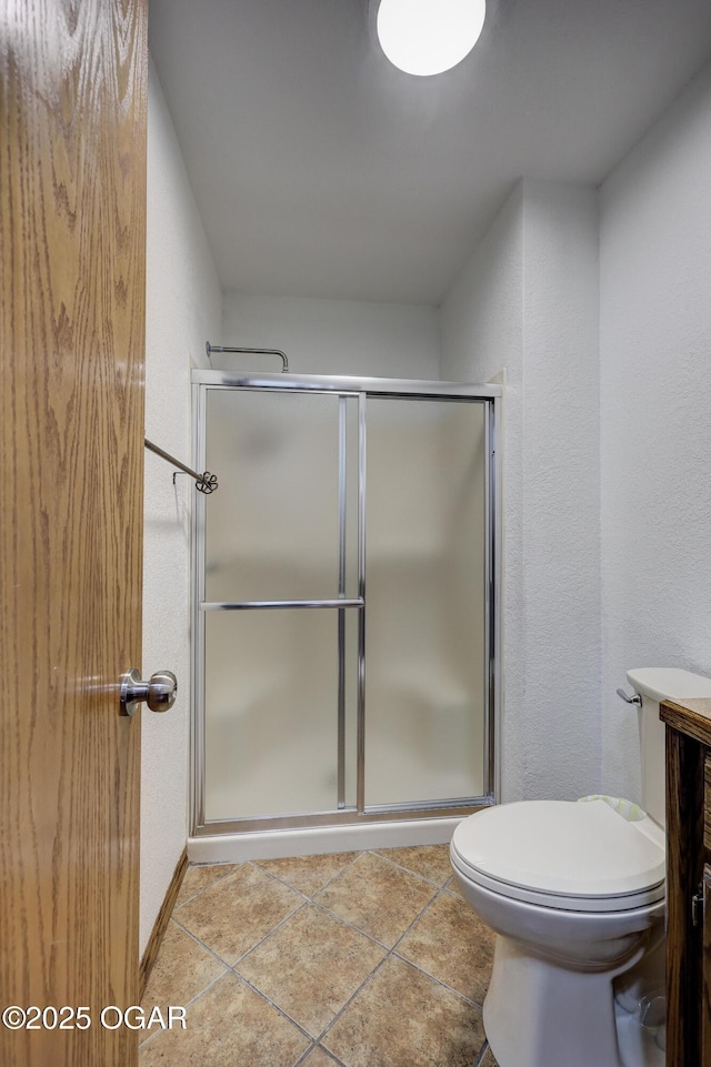 bathroom with an enclosed shower, tile patterned floors, and toilet