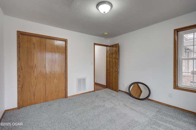 unfurnished bedroom featuring carpet floors, a closet, and a textured ceiling