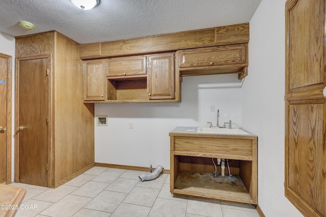 washroom featuring light tile patterned flooring, sink, cabinets, a textured ceiling, and hookup for a washing machine