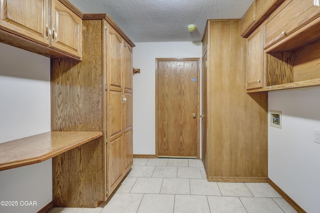 clothes washing area featuring cabinets, hookup for a washing machine, and a textured ceiling