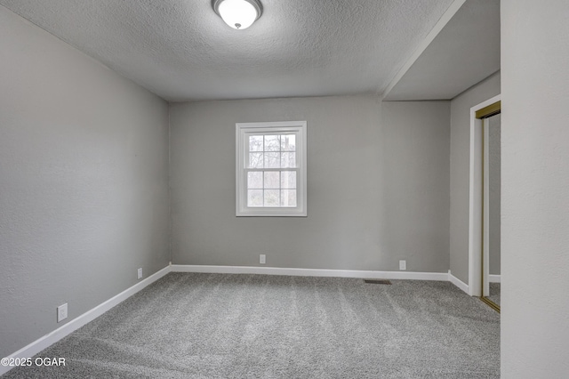 unfurnished room with carpet and a textured ceiling