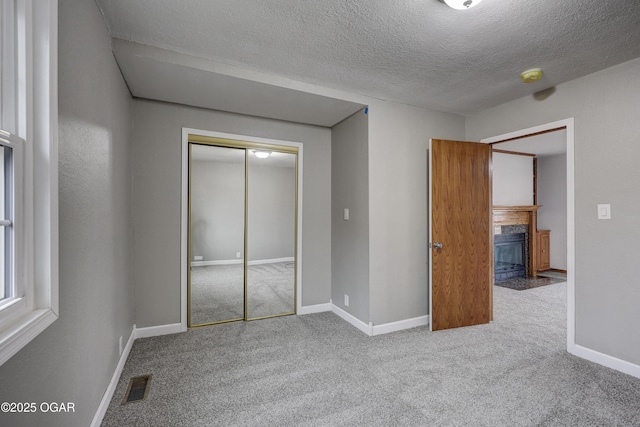 unfurnished bedroom with carpet, a textured ceiling, and a closet