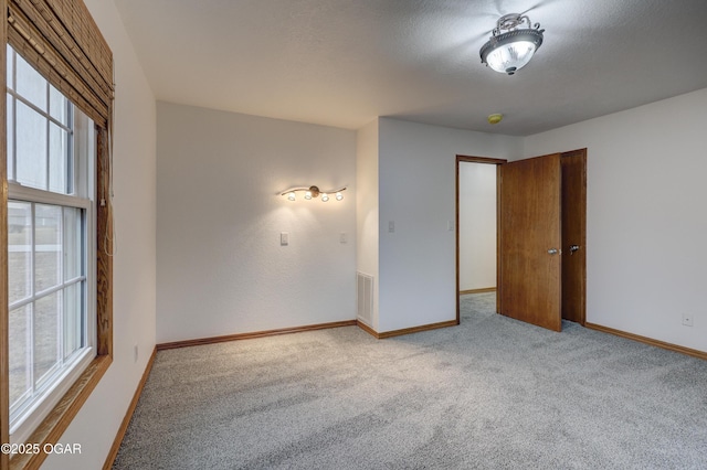 unfurnished room with light carpet and a textured ceiling