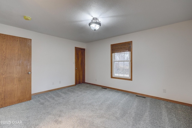 carpeted empty room with a textured ceiling