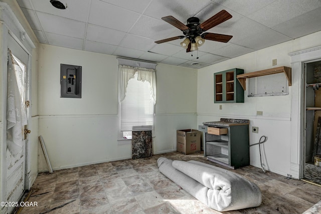 interior space featuring a paneled ceiling, a wealth of natural light, electric panel, and ceiling fan