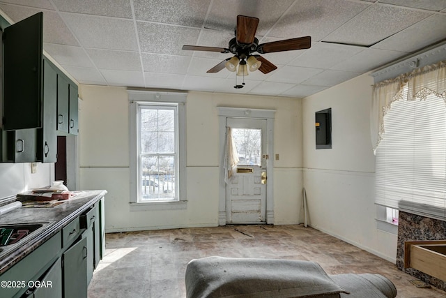 interior space featuring ceiling fan, electric panel, and a drop ceiling