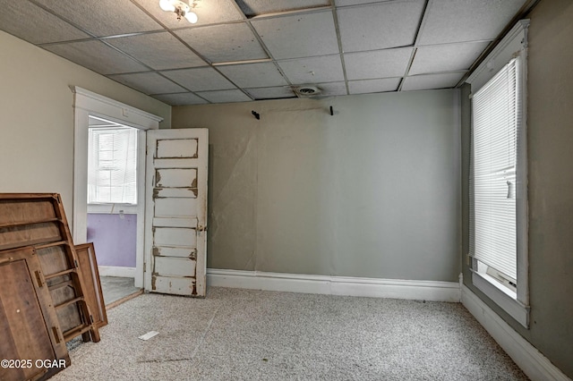 carpeted empty room featuring a paneled ceiling