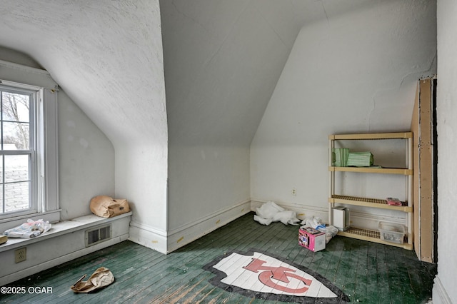 bonus room featuring vaulted ceiling, a healthy amount of sunlight, dark wood-type flooring, and a textured ceiling