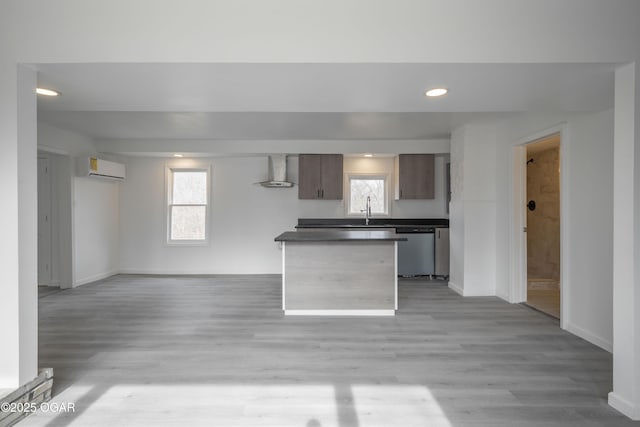 kitchen featuring dishwasher, wall chimney range hood, a wall mounted AC, and light wood-type flooring