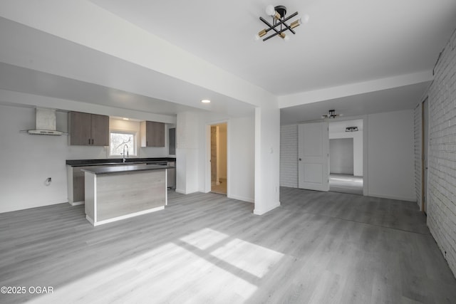 unfurnished living room featuring brick wall, sink, and light hardwood / wood-style flooring