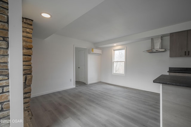 unfurnished living room with hardwood / wood-style floors and a wall mounted AC