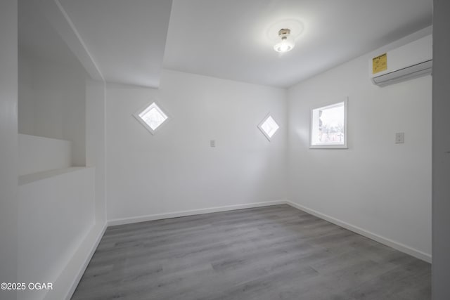 spare room featuring plenty of natural light, a wall mounted air conditioner, and light hardwood / wood-style flooring