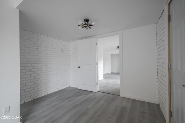 spare room with hardwood / wood-style floors and brick wall