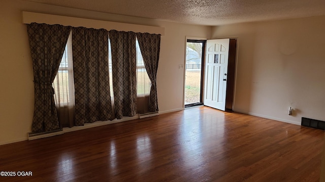 unfurnished room featuring hardwood / wood-style flooring, a wealth of natural light, and a textured ceiling