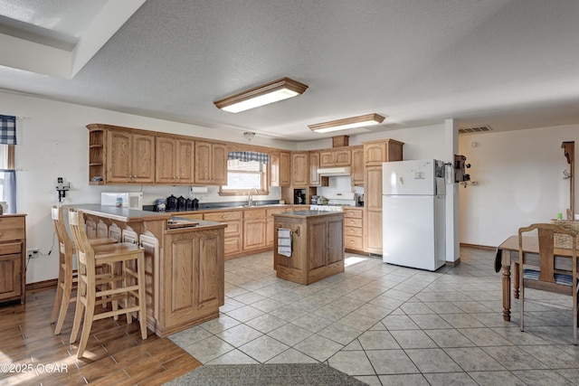 kitchen featuring a kitchen island, sink, a kitchen bar, kitchen peninsula, and white appliances